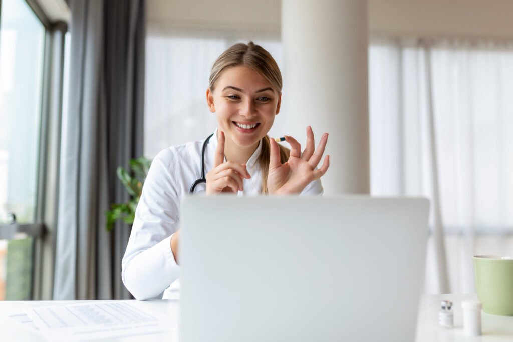 Attractive female doctor talking while explaining medical treatment to patient through a video call with laptop in the consultation.