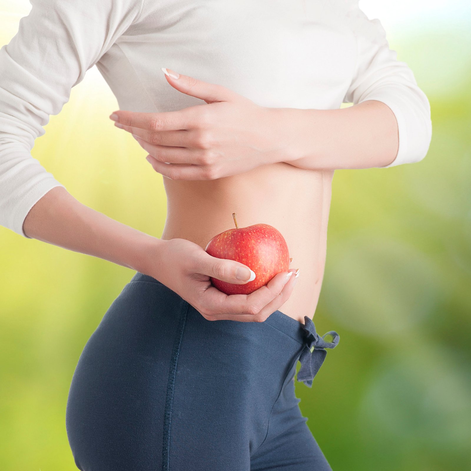 Woman showing an apples in close up of belly stomach