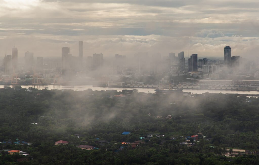 Bangkok, thailand -Aug 29, 2021 : An impressive aerial top view of skyscrapers at downtown Bangkok city along the chao phraya river in morning fog. No focus, specifically.