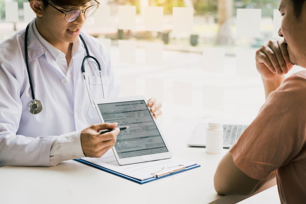Asian doctor talking the patient at clinic while using the tablet explaining the patient condition and the treatment result.