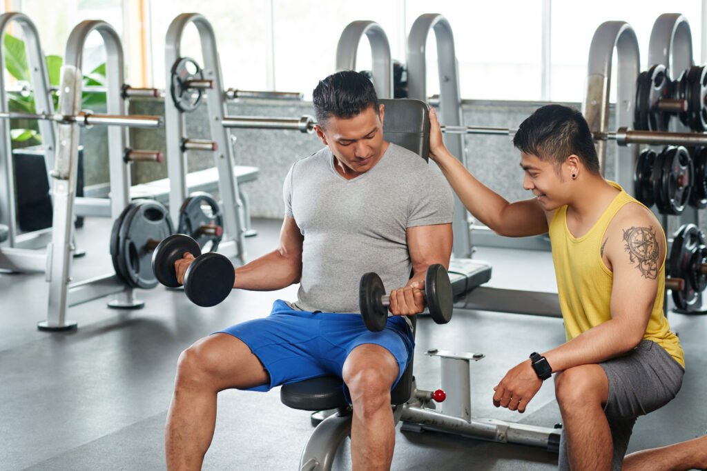 Fitness instructor controlling how bodybuilder working out with weights