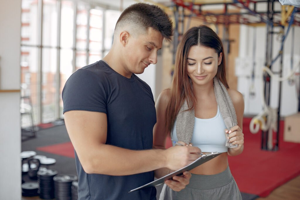 Handsome man in a gym. Sportspeople in a sportswear. Woman training with coach