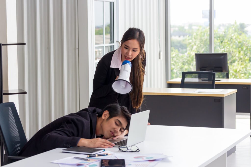 Asian female secretary wakes up a young business boss by a megaphone